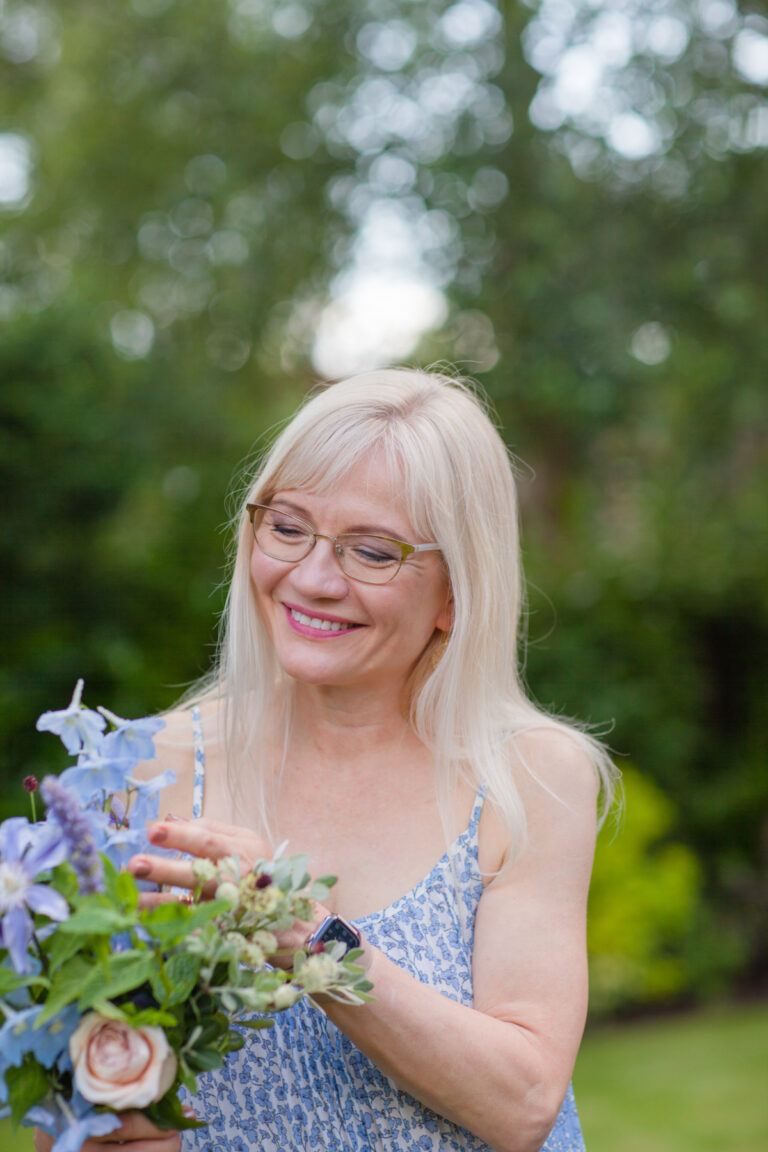 Reclaim your summer header image - April Harris wearing a blue summer dress and holding a bouquet of flowers outside in the garden