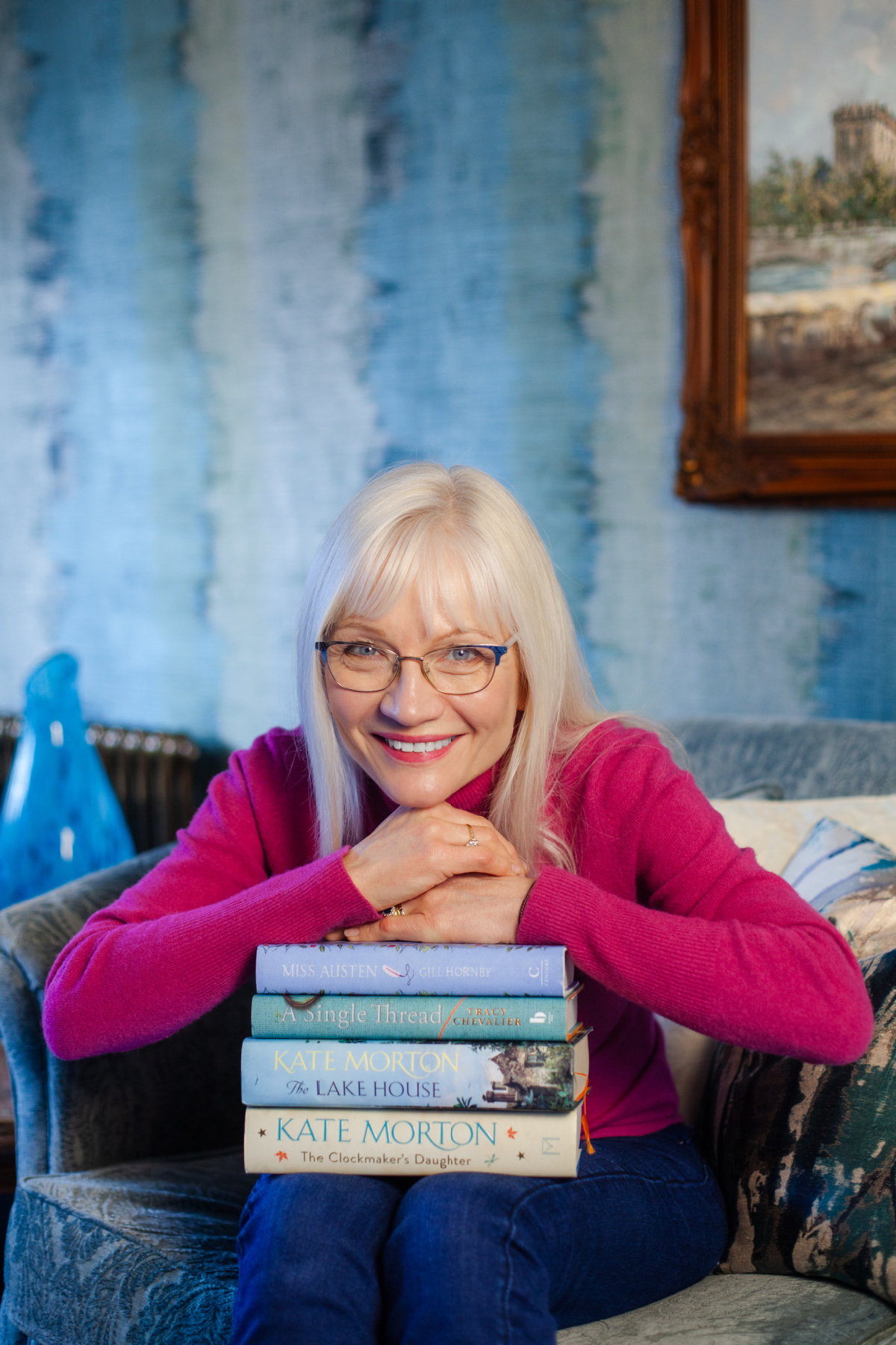 25 Best Summer Reads Header image - April J Harris holding a stack of books and resting her arms on them