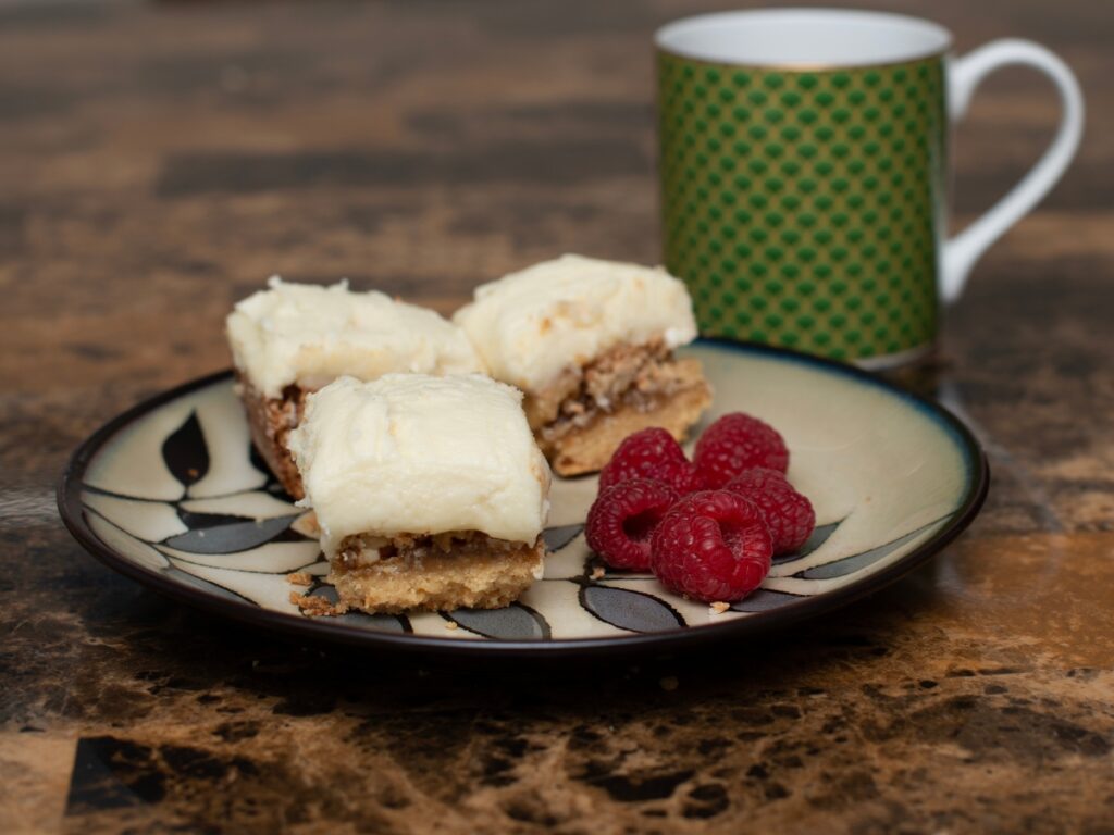 3 Old-Fashioned Lemon and Walnut Squares served on a plate with a side of raspberries