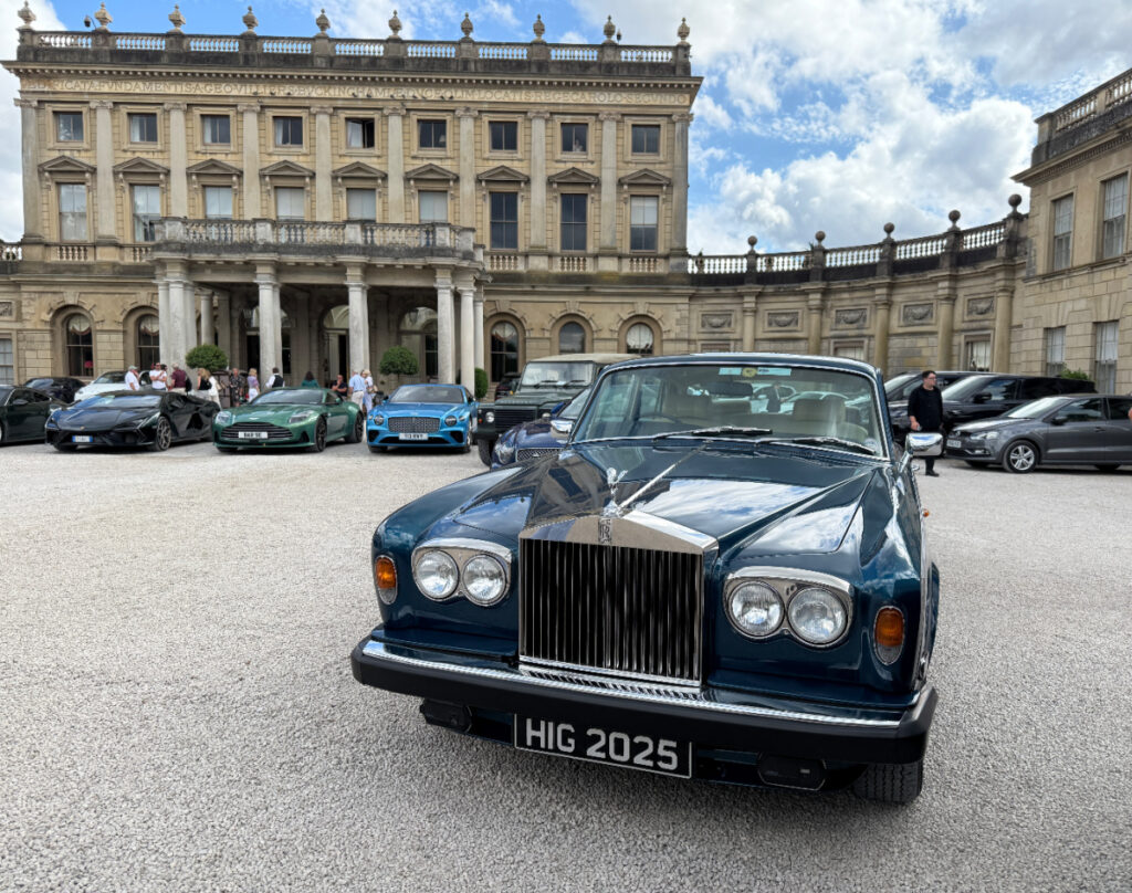A 1977 Rolls-Royce Silver Shadow II photographed in front of Cliveden House. There are other classic cars in the background.